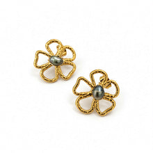 Load image into Gallery viewer, A pair of gold flower-shaped stud earrings with textured five-petal outlines and a dark gray pearl center, shown on a clean white background.