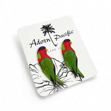 Load image into Gallery viewer, A pair of colorful parrot stud earrings mounted on a white display card. The card features the brand name 'Adorn Pacific' and a black palm tree illustration.