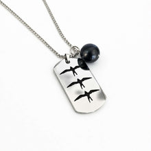 Load image into Gallery viewer, A silver-toned dog tag necklace with three flying bird silhouettes, featuring a black pearl bead charm, shown on a clean white background.