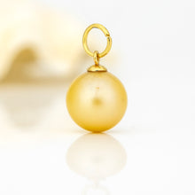 Load image into Gallery viewer, A gold charm featuring a smooth, lustrous round pearl pendant suspended from a small gold loop, set against a bright white background with a soft reflection.