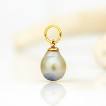 Load image into Gallery viewer, A gold pendant charm featuring a teardrop-shaped baroque pearl with iridescent gray, blue, and green hues, suspended from a polished gold ring on a white reflective surface.