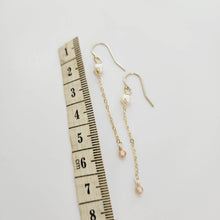 Load image into Gallery viewer, A pair of freshwater pearl drop earrings with glass bead detail, hanging from 14k gold fill metal hooks, displayed against a white background.