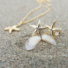 Load image into Gallery viewer, Starfish shaped earrings in gold on sand