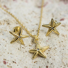 Load image into Gallery viewer, Starfish shaped earrings and necklace in gold on a textured surface with blurred background