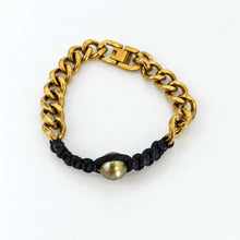 Load image into Gallery viewer, A gold-tone chain link bracelet with a black braided cord wrap and a single round pearl bead at the center, shown on a plain white background.
