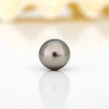 Load image into Gallery viewer, Single pearl on a reflective surface with a blurred gold object in the background
