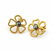 Load image into Gallery viewer, A pair of gold flower-shaped stud earrings with textured petals and a dark gray oval pearl in the center, set against a plain white background.
