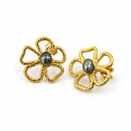 A pair of gold flower-shaped stud earrings with textured petals and a dark gray oval pearl in the center, set against a plain white background.