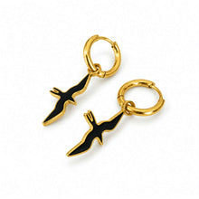 Load image into Gallery viewer, A pair of gold hoop earrings with dangling black and gold bird-shaped charms, shown on a clean white background.
