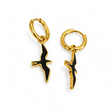 Load image into Gallery viewer, A pair of gold hoop earrings with dangling bird-shaped charms filled with black enamel, shown on a plain white background.
