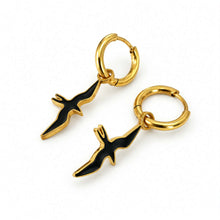 Load image into Gallery viewer, A pair of gold hoop earrings with dangling black and gold bird charms, displayed on a clean white background.
