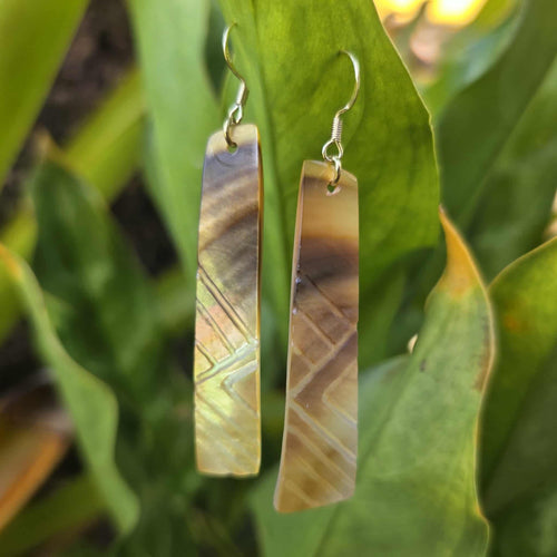Pair of bar-shaped earrings with a geometric pattern on a green leaf background