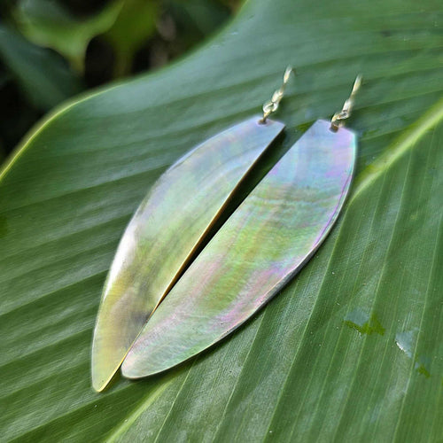 Iridescent leaf-shaped earrings on a green leaf background