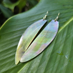 Iridescent leaf-shaped earrings on a green leaf background