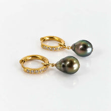 Load image into Gallery viewer, A pair of gold huggie hoop earrings with small clear stones along the front, each suspending pearls, displayed on a clean white surface.
