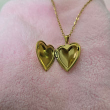 Load image into Gallery viewer, Gold heart-shaped locket on a pink surface
