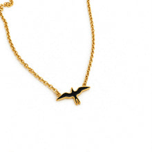 Load image into Gallery viewer, A gold chain necklace featuring a small flying bird pendant with black enamel fill, shown on a plain white background.
