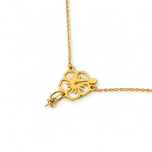 Load image into Gallery viewer, A gold-toned necklace featuring a cutout floral pendant with pearl setting, shown against a plain white background.
