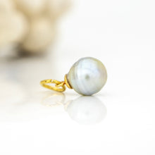 Load image into Gallery viewer, A single gold pendant featuring a large, round, lustrous pearl with iridescent blue-gray tones, resting on a reflective white surface.

