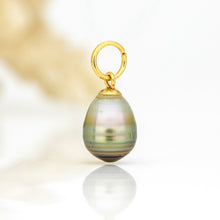 Load image into Gallery viewer, A teardrop-shaped freshwater pearl pendant with iridescent green and gold hues, attached to a matching gold jump ring clasp, shown on a reflective white surface.
