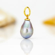 Load image into Gallery viewer, A teardrop-shaped baroque pearl pendant with an iridescent blue-purple sheen, suspended from a polished gold bail, set against a clean white background with a soft reflection.
