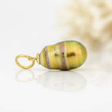 Load image into Gallery viewer, A teardrop-shaped pendant with a gold-tone ring loop, featuring a glossy, iridescent bead with green, yellow, and brown bands, resting on a reflective white surface.
