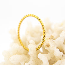 Load image into Gallery viewer, Gold ring with twisted design on a white coral background
