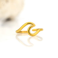 Gold wave-shaped ring on a white background