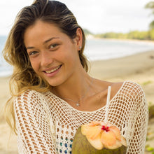 Load image into Gallery viewer, Mini starfish earrings and necklace worn by a model on a beach holding a coconut
